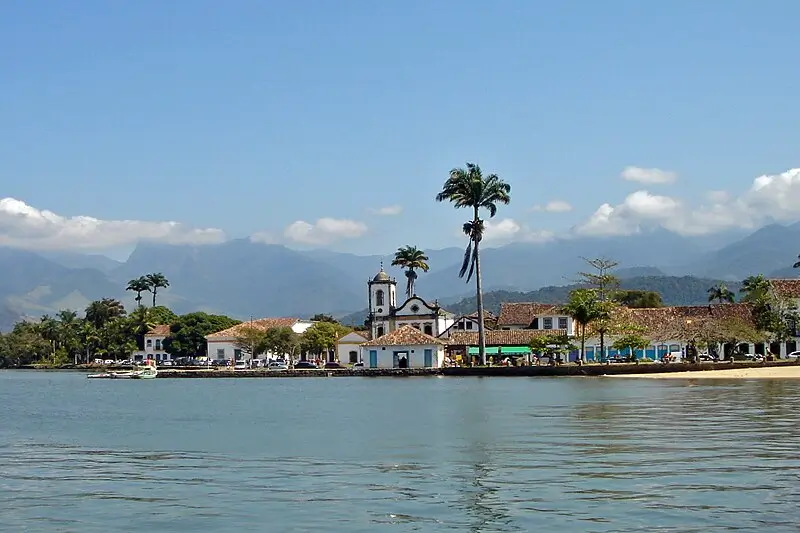 Vista do centro histórico de Paraty, com suas construções coloniais à beira-mar, cercadas por montanhas e coqueiros, no litoral sul do Rio de Janeiro