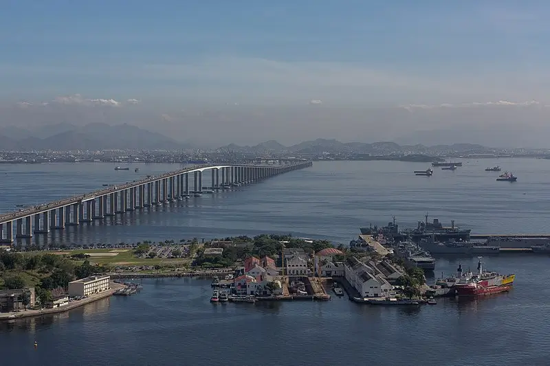 Vista aérea da Ponte Rio-Niterói atravessando a Baía de Guanabara, no Rio de Janeiro, com embarcações e a paisagem urbana ao fundo