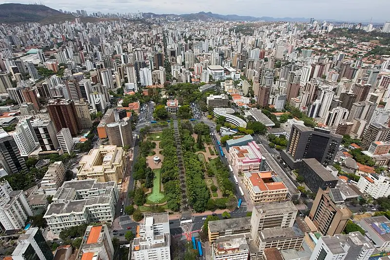 Vista aérea de Belo Horizonte com a Praça da Liberdade ao centro, cercada por edifícios altos e áreas urbanas da capital mineira