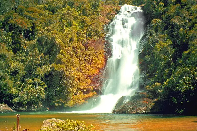 Cachoeira Santo Isidro em meio à vegetação da Mata Atlântica, com queda d’água em várias camadas formando um poço de águas claras