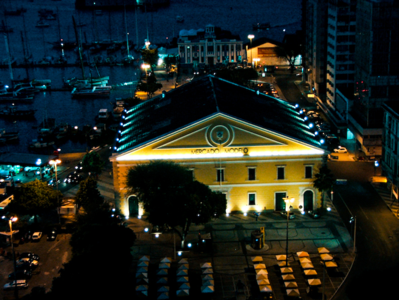 Vista noturna do Mercado Modelo iluminado, em Salvador, com a Baía de Todos-os-Santos ao fundo