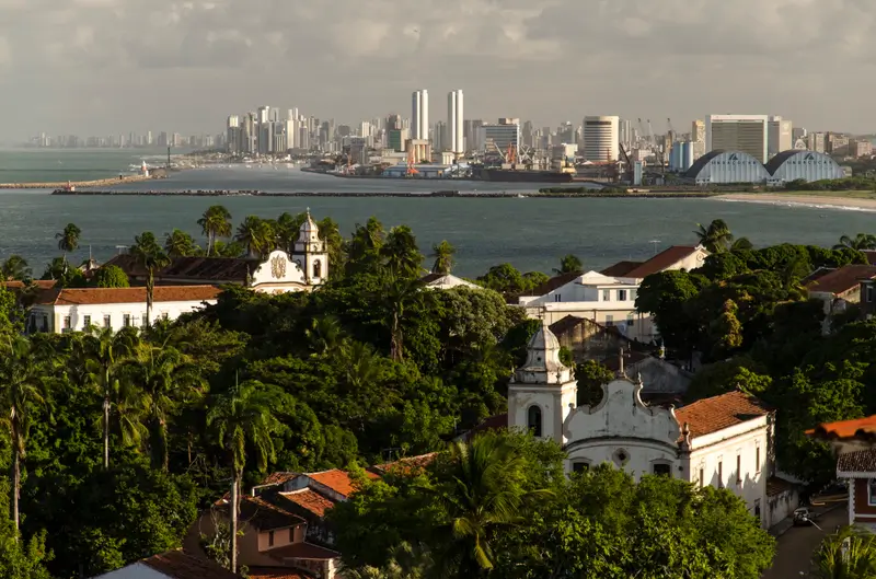 Vista panorâmica de Olinda com igrejas históricas e, ao fundo, a cidade de Recife e o mar
