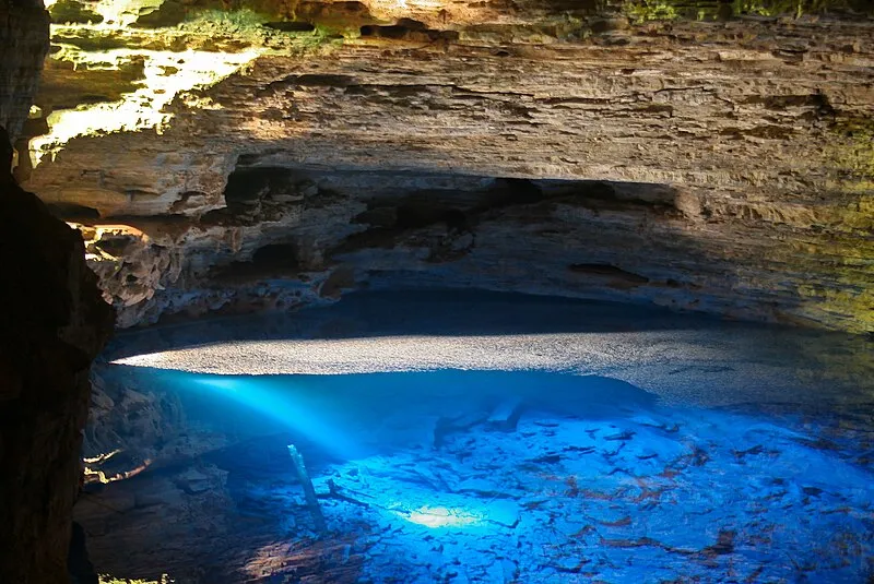 Poço Encantado com água azul cristalina iluminada por feixe de luz solar na Chapada Diamantina