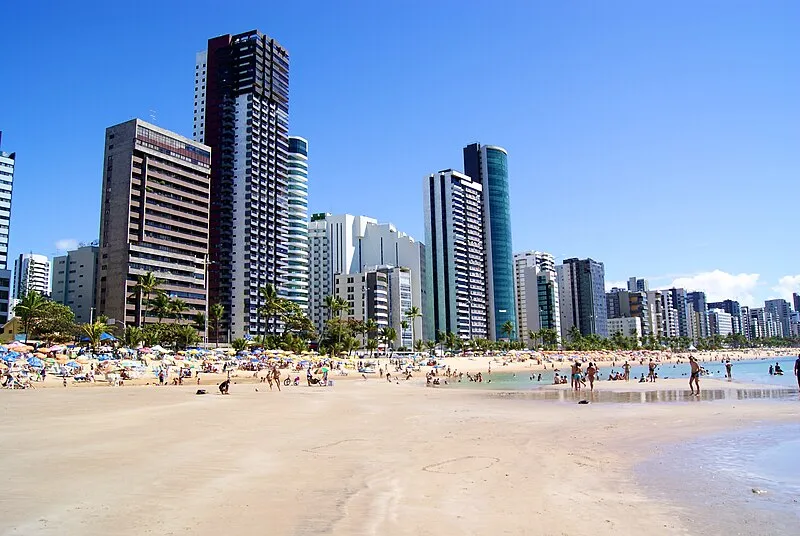 Praia de Boa Viagem em Recife com prédios altos e banhistas na areia