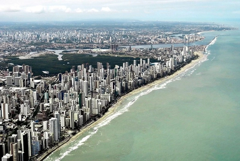 Vista aérea de Recife com arranha-céus na orla e mar verde em Pernambuco