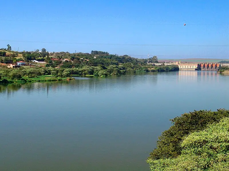 Vista do Rio Tietê com vegetação nas margens e a barragem entre os municípios de Barra Bonita e Igaraçu do Tietê ao fundo