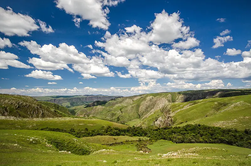 Vista panorâmica da Serra da Canastra com campos verdes, montanhas e céu azul com nuvens espalhadas em Minas Gerais