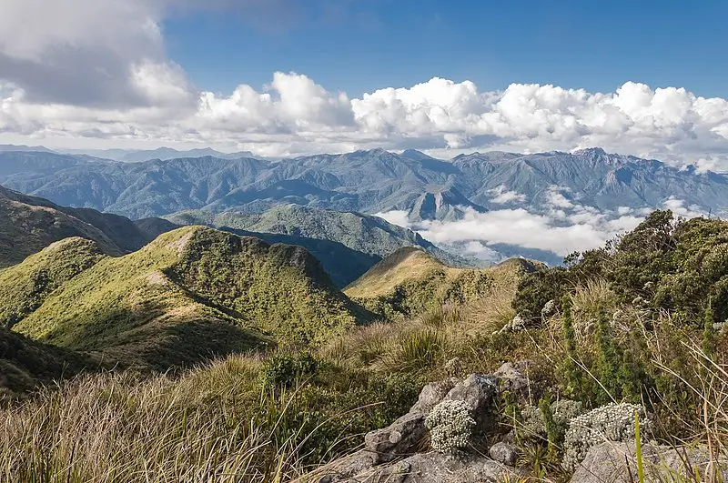 Vista panorâmica da Serra da Mantiqueira com montanhas cobertas por vegetação nativa e nuvens se formando entre os vales