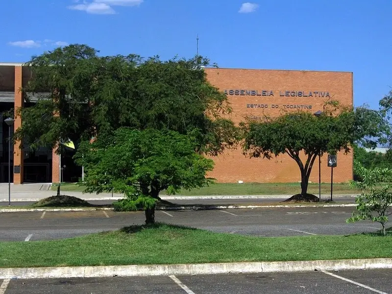 Fachada da Assembleia Legislativa do Tocantins, em Palmas, com área verde e estacionamento ao redor.