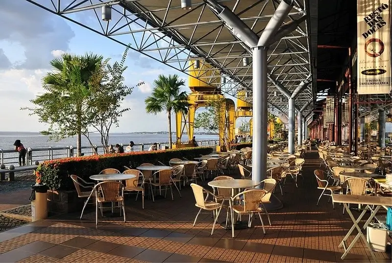 Área externa da Estação das Docas em Belém com mesas, palmeiras e vista para a Baía do Guajará