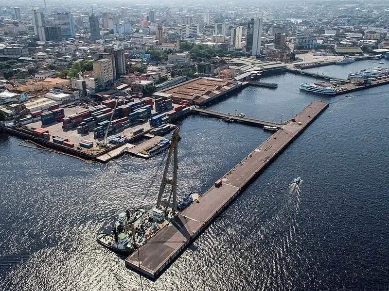 Vista aérea do Porto Flutuante de Manaus às margens do Rio Negro, com área portuária e centro urbano ao fundo.