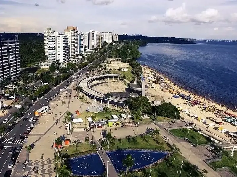 Vista aérea da Praia da Ponta Negra em Manaus, com orla urbana e o Rio Negro ao fundo.