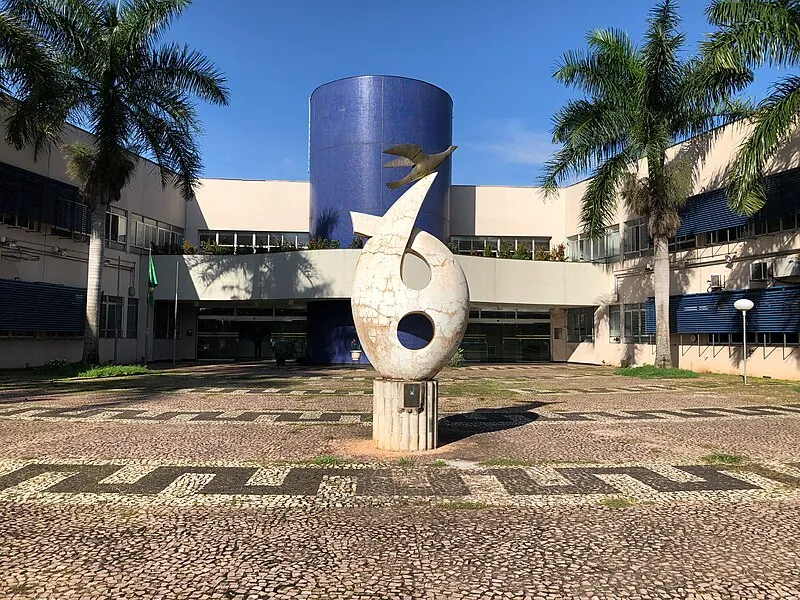 Fachada da reitoria da Universidade Federal de Goiás com escultura central e palmeiras
