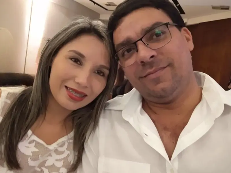 Casal sorrindo em ambiente interno, bem vestidos para ocasião especial