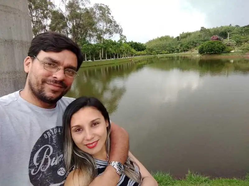 Casal abraçado à beira de um lago em meio à natureza