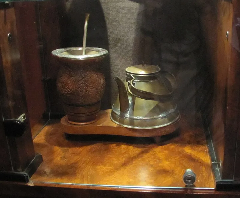 Conjunto de chimarrão com chaleira, cuia e bomba em exposição de museu