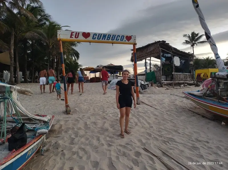 Mulher entrando na praia de Cumbuco sob o cartaz "EU ❤ CUMBUCO"