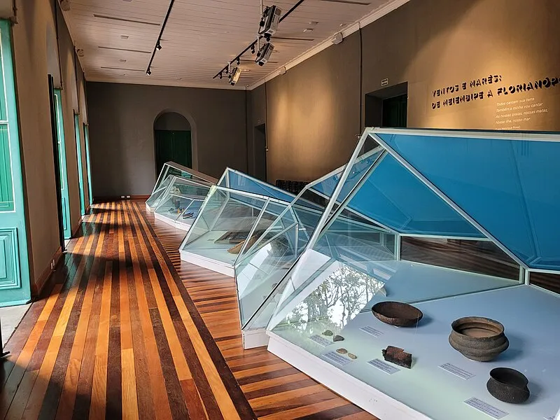 sala do Museu de Florianópolis com vitrines de vidro exibindo peças arqueológicas