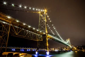 Ponte Hercílio Luz iluminada à noite em Florianópolis, Santa Catarina. Por FREITASFOTOS, CC BY-SA 4.0, via Wikimedia Commons