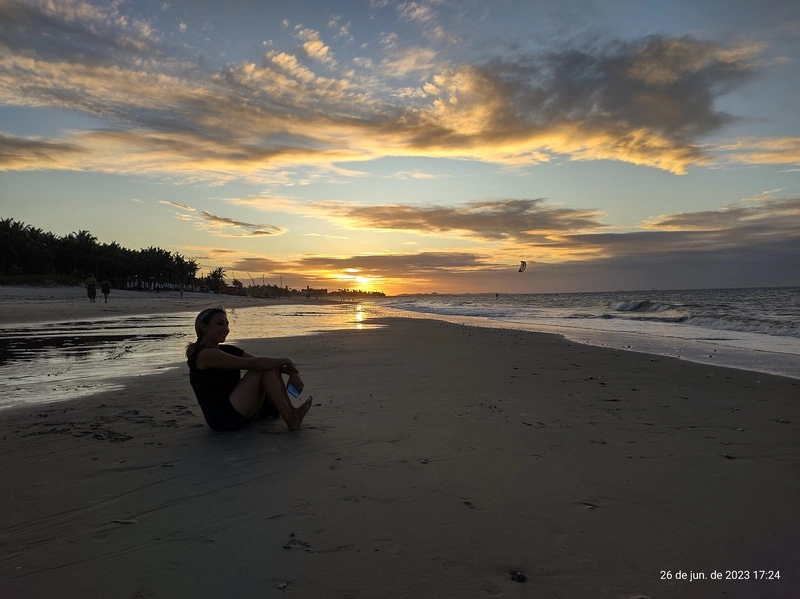 Mulher sentada na praia de Cumbuco durante o pôr do sol