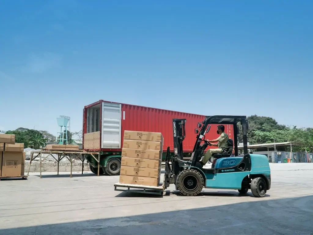 Empilhadeira movimentando um dos tipos de carga frágil em pallets para dentro de um contêiner.