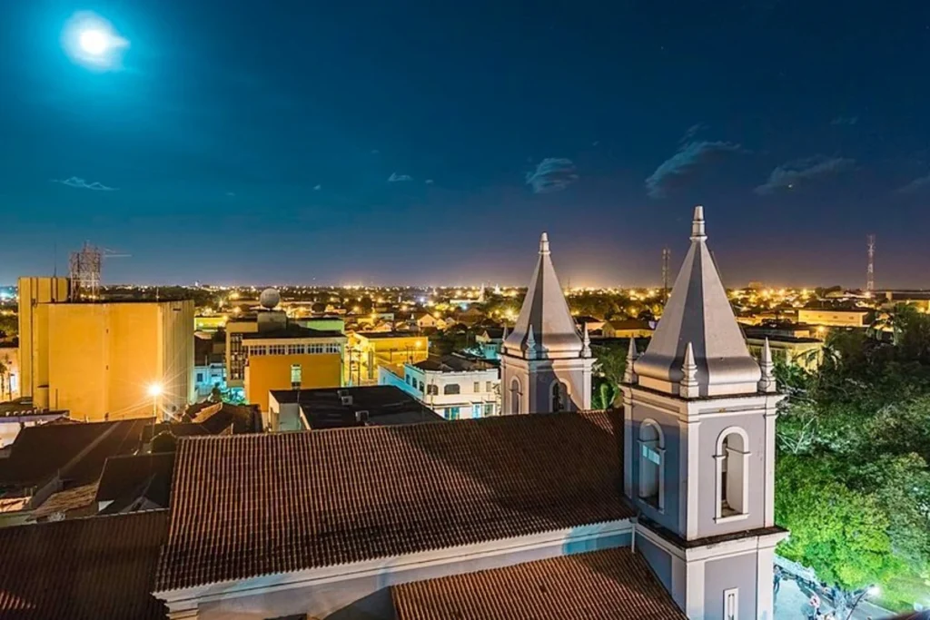 Vista noturna do centro de Parnaíba com igreja iluminada