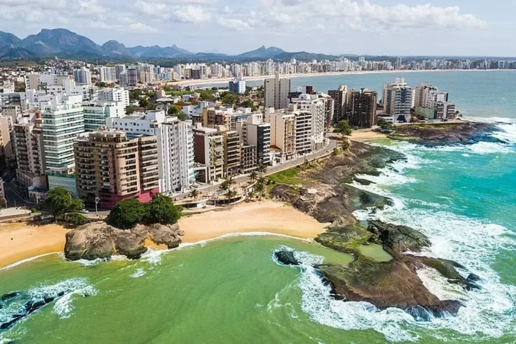 Vista aérea de Guarapari ES com prédios à beira-mar e praias paradisíacas