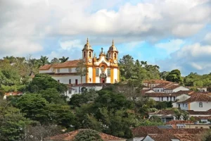 Vista da Igreja Matriz de Santo Antônio em Tiradentes, Minas Gerais, cercada por casas coloniais e vegetação