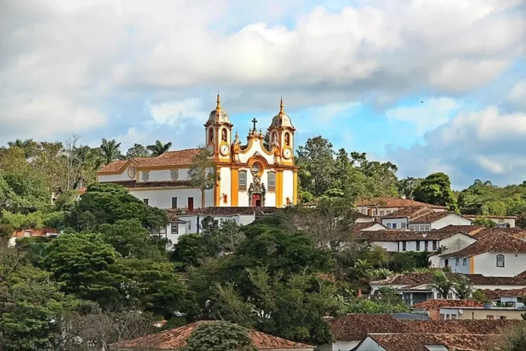 Vista da Igreja Matriz de Santo Antônio em Tiradentes, Minas Gerais, cercada por casas coloniais e vegetação