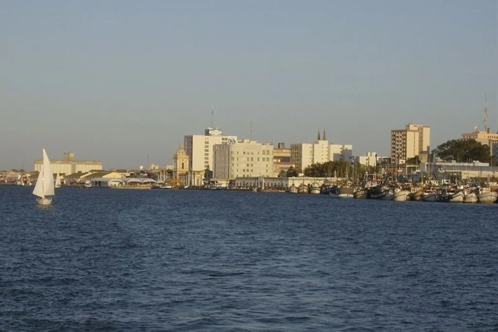 Vista da orla de Rio Grande RS com barcos de pesca e prédios ao fundo