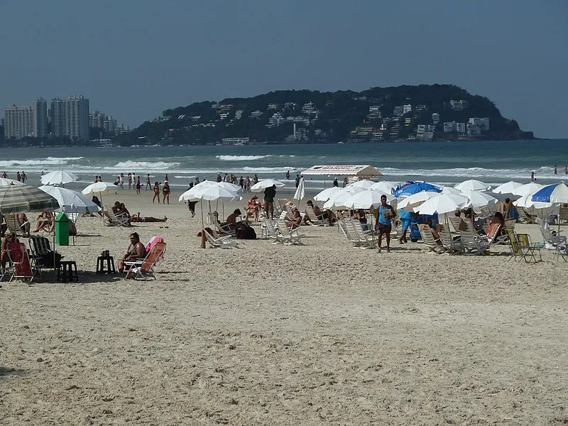 Praia da Enseada no Guarujá com guarda-sóis e o Morro do Maluf ao fundo
