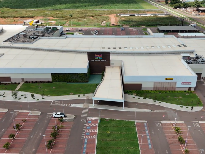 Vista aérea do Shopping Sinop mostrando fachada moderna e amplo estacionamento