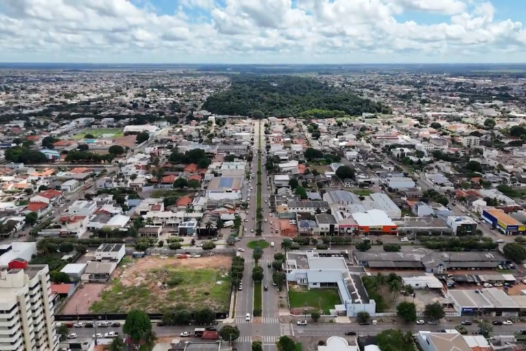 Vista aérea de Sinop mostrando avenidas, áreas residenciais e uma extensa área verde ao fundo