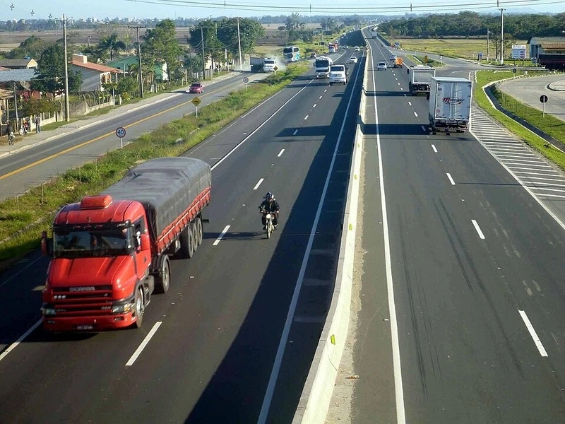 Trecho duplicado da BR-101 em Santa Catarina com caminhões, veículos leves e fluxo intenso de tráfego rodoviário.