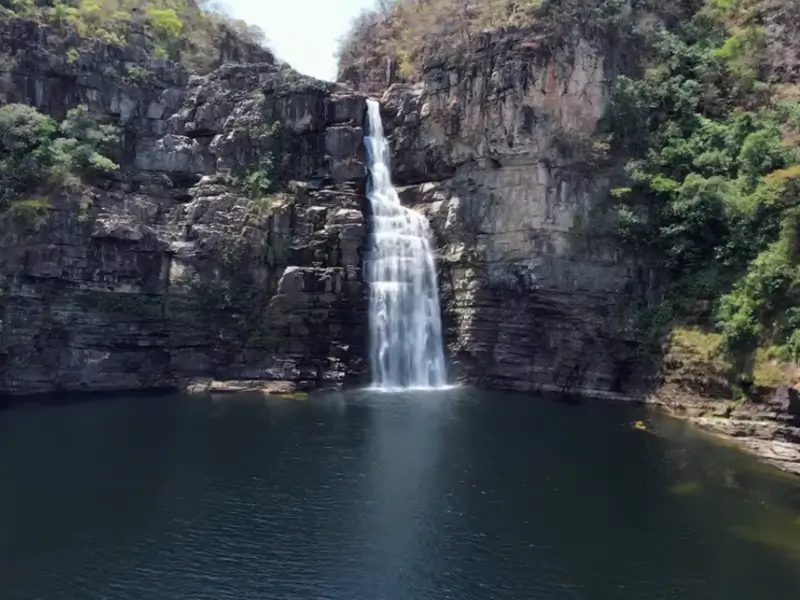 Cachoeira do Garimpão caindo em um grande poço escuro entre paredões rochosos na Chapada dos Veadeiros.