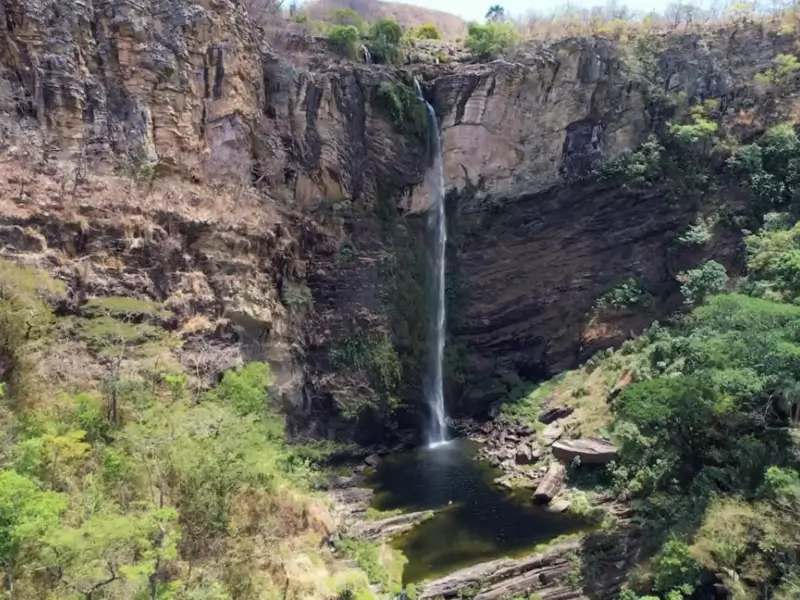 Cachoeira alta caindo em um poço escuro entre paredões rochosos na Chapada dos Veadeiros.