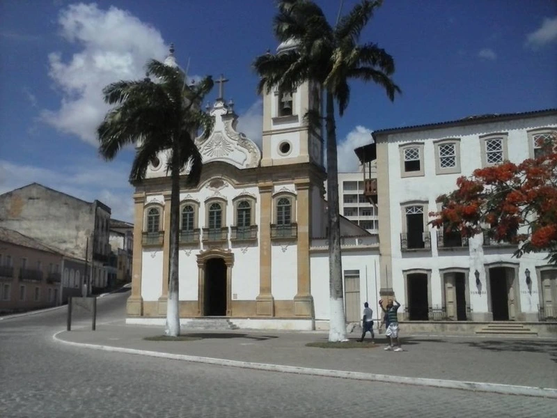 Igreja de Nossa Senhora da Corrente em Penedo com fachada histórica e palmeiras ao redor.