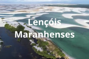 Vista aérea das dunas e lagoas azul-esverdeadas dos Lençóis Maranhenses sob céu parcialmente nublado.