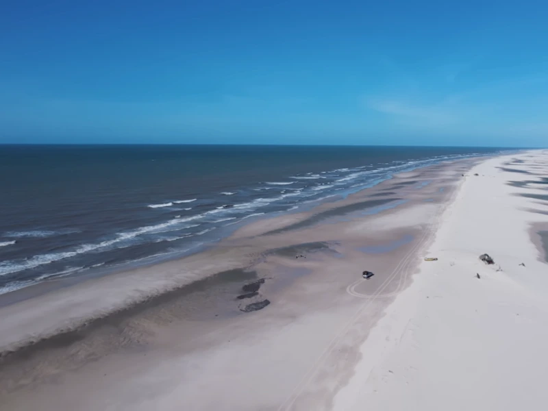 Vista aérea da Praia da Travosa com faixa extensa de areia clara e mar azul no Maranhão.