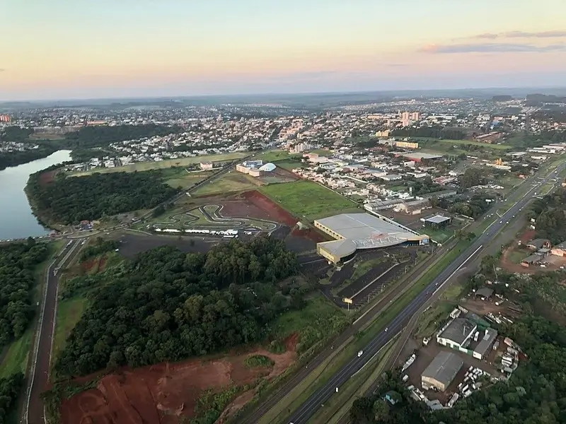 Trecho da BR-277 próximo ao perímetro urbano de Cascavel, Paraná, com áreas urbanas, vegetação e infraestrutura rodoviária ao redor.