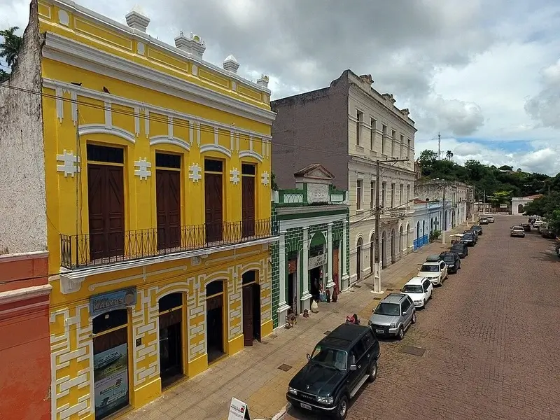 Prédios históricos no Porto Geral de Corumbá, Mato Grosso do Sul, com arquitetura preservada e rua de paralelepípedos.